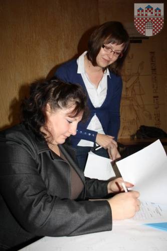 : Iwona Kot z Żarek podpisuje dokumenty w ramach projektu, obok Agnieszka Pala-Czyż z MOPS w Żarkach.